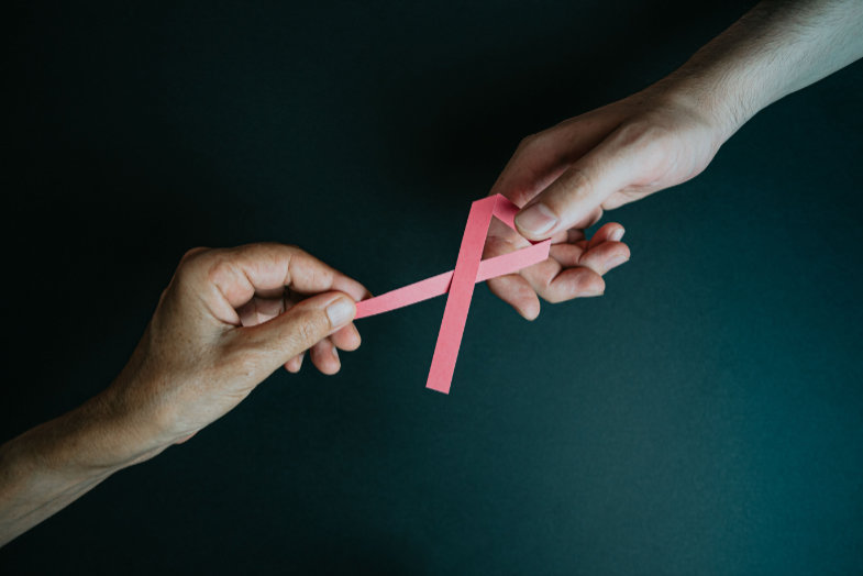 Photo of two hands holding a pink charity box